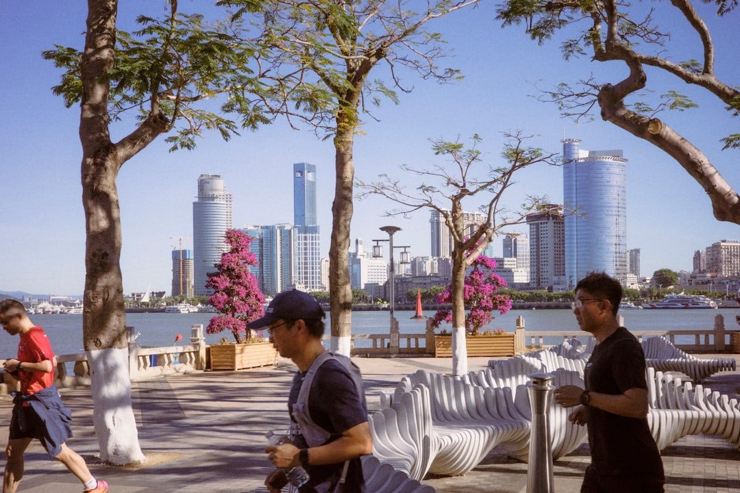 People walking along a waterfront with city skyline.